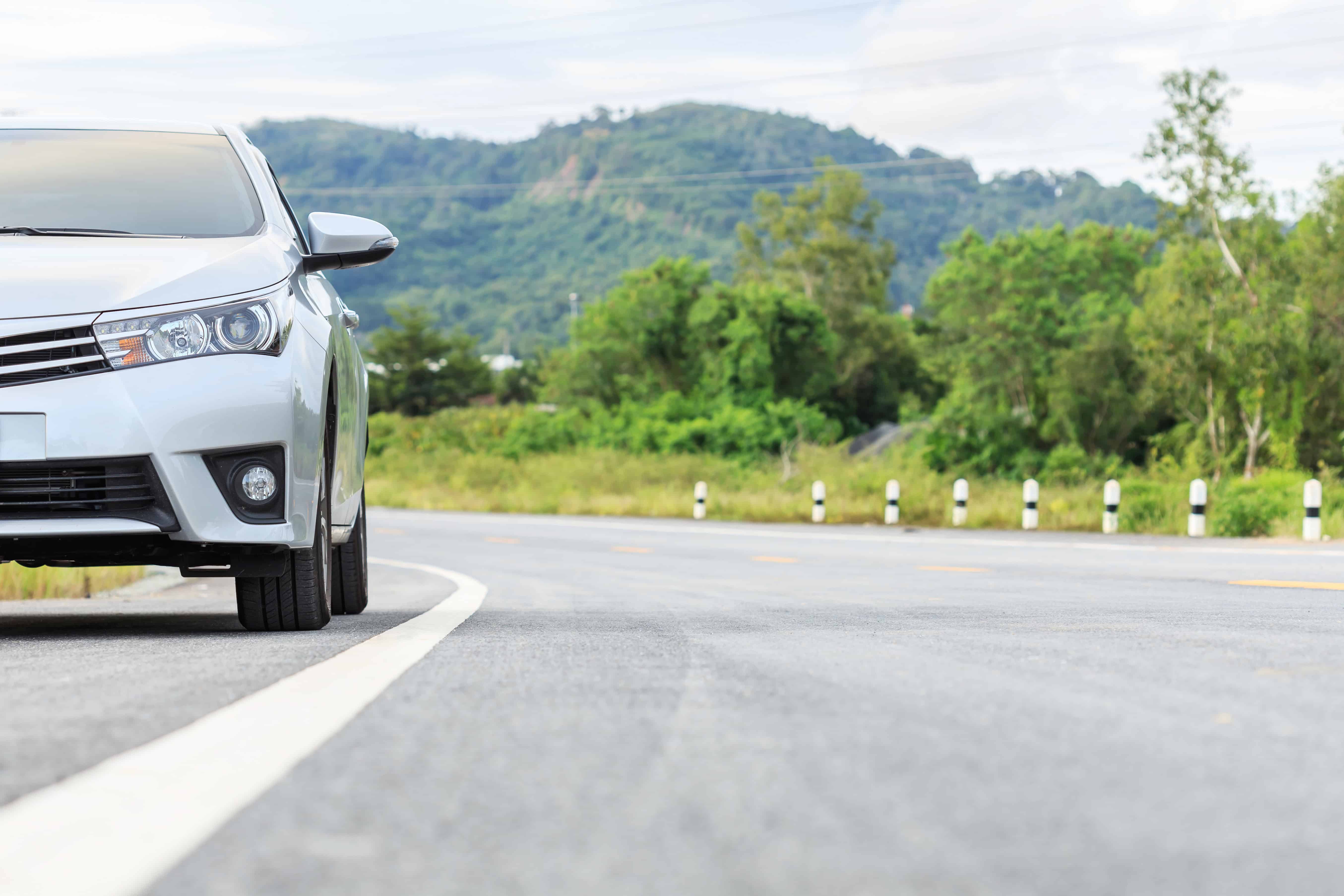 passenger car driving down a road with a mountain in the background.jpg